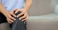 Close up shot of senior man suffering from knee pain sitting on sofa Royalty Free Stock Photo