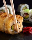 Close-up shot of several rolls of sushi with chopsticks on a black stone-plate Royalty Free Stock Photo