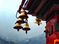 Close-up shot of shiny bells hanging off of a red building on a misty background