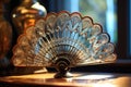 close-up shot of a single hand fan with intricate design on a glass table