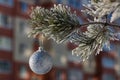 Close up shot of a single white glittering Christmas ball decoration hanging off a Christmas tree outside. Tree and ball covered Royalty Free Stock Photo