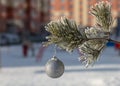 Close up shot of a single white glittering Christmas ball decoration hanging off a Christmas tree outside. Tree and ball covered Royalty Free Stock Photo