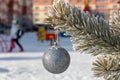 Close up shot of a single white glittering Christmas ball decoration hanging off a Christmas tree outside. Tree and ball covered Royalty Free Stock Photo