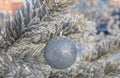 Close up shot of a single white glittering Christmas ball decoration hanging off a Christmas tree outside, partially covered in Royalty Free Stock Photo