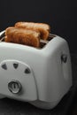 Close-up shot of slightly burnt white bread toasts sticking out of a toaster on the black background. Ready toasts with a dark Royalty Free Stock Photo