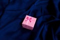 Close up shot of small gift wrapped with pink ribbon on a bleu silky background