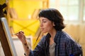 A close up shot of a small table full of artistic equipment that is being used by by a beautiful painter who is painting Royalty Free Stock Photo