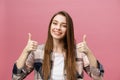 Close-up shot of smiling pretty girl showing thumb up gesture. Female isolated over pink background in the studio. Royalty Free Stock Photo