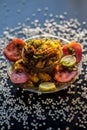 Close up shot of spicy tasty sabudana khichdi or sago ball khichdi along with some sliced tomatoes, some cut lemons in a glass