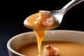 Close-up shot of a spoonful of lobster bisque soup with visible chunks of tender lobster meat