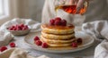A close-up shot of a stack of pancakes topped with raspberries and drizzled with maple syrup. Royalty Free Stock Photo