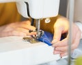 Female seamstress sewing or stitching fabric with professional machine