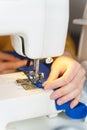 Female seamstress sewing or stitching fabric with professional machine