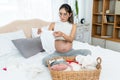 Close-up shot of teenage mother, pregnant, pregnant, near delivery, sitting and preparing clothes for baby to be born, baby