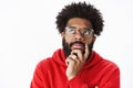 Close-up shot of thoughtful african american man rubbing beard and looking at upper left corner focused, thinking Royalty Free Stock Photo