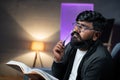 close up shot of Thoughtful Young Indian beard man while reading book during night - concept of dreaming or imagination Royalty Free Stock Photo