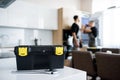 Close up shot of toolbox and wrench lying on the table. Repairman in uniform fixing refrigerator in the kitchen, while