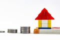 Close up shot of a toy house on note bundle and piled up coins in Home Loan concept