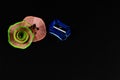 Close up shot of two beautiful pencil shavings in round flower like shape and a blue sharpener on black background Royalty Free Stock Photo