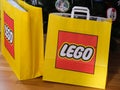 A close-up shot of two Lego paper bags with a Lego sets in it near a Christmas tree