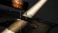Water dripping from a rusty old pipe onto a dark, wet surface under a dramatic light beam Royalty Free Stock Photo