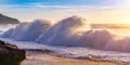 close up shot of waves hitting the coastline of portugal at the beach at calm orange sunset ocean. surreal selective focus shot