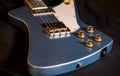 A close-up shot of a well used looking blue Theta guitar resting on a black cloth