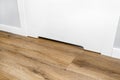 Close up shot of a white door with a vent in a modern home with vinyl planks on the floor. Royalty Free Stock Photo