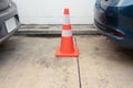 Close up shot of white-orange traffic cone placing in the space between the cars head and tail in urban parking lot shows the Royalty Free Stock Photo