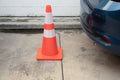 Close up shot of white-orange traffic cone placing in the space between the cars head and tail in urban parking lot shows the Royalty Free Stock Photo