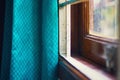 Close-up shot of a window with old blue curtains in the afternoon