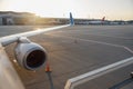 Close up shot of a wing of commercial airplane near the terminal in an airport at the sunset