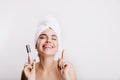 Close-up shot of woman with perfect face. Smiling girl after shower poses with skin corrector on white background.