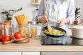 Woman cooking tasty rice with vegetables on stove in kitchen, closeup Royalty Free Stock Photo
