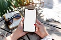 A close up shot of a woman& x27;s hand holding an phone with a blank screen sitting at an outdoor cafe table, notebook on Royalty Free Stock Photo