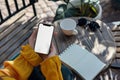 A close up shot of a woman's hand holding an phone with a blank screen sitting at an outdoor cafe table, notebook on Royalty Free Stock Photo