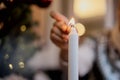 Close-up shot of a woman`s hand lighting a candle using matches. Christmas holiday Royalty Free Stock Photo