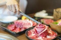 Close-up shot of a woman\'s hand tongs wagyu beef on a plate to grill in a charcoal grill. at a Japanese restaurant