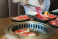 Close-up shot of a woman's hand tongs wagyu beef on a plate to grill in a charcoal grill. at a Japanese restaurant