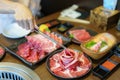 Close-up shot of a woman's hand tongs wagyu beef on a plate to grill in a charcoal grill. at a Japanese restaurant