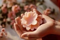 Woman\'s hands holding a flower-shaped wax shaving product, highlighting the connection between femininity,