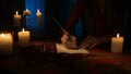 Woman sitting in the dark room and writing a letter with ink feather pen on the old paper. Royalty Free Stock Photo