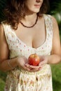 Impersonal brunette in the summer dress holding the red apple in front of her Royalty Free Stock Photo