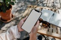 A close up shot of a woman& x27;s hand holding an phone with a blank screen sitting at an outdoor cafe table, notebook on Royalty Free Stock Photo