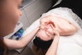 Close-up shot of a woman& x27;s head doing a facial massage on a treatment table. Therapist applying pressure with thumbs Royalty Free Stock Photo