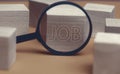 Close-up shot of wooden blocks with JOBS sign and magnifying glass on table. search concept