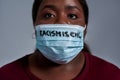 Close up shot of young african american woman wearing protective face mask with Racism is evil text looking at camera Royalty Free Stock Photo