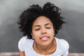 Close-up shot of young black woman smiling and closing her eyes with happy face expression, dreaming and enjoying warm summer wind