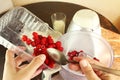 Close-up shot of young caucasian woman`s hands pouring raspberries from plastic container into food processor for making raspberry