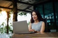 Close up shot of a young female university student writes a note and assignment with a laptop beside outside the cafe with blur